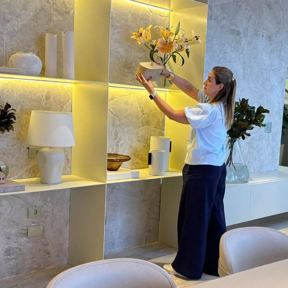 Personal organizer da Ro Organiza posicionando arranjo decorativo em ambiente de alto padrão